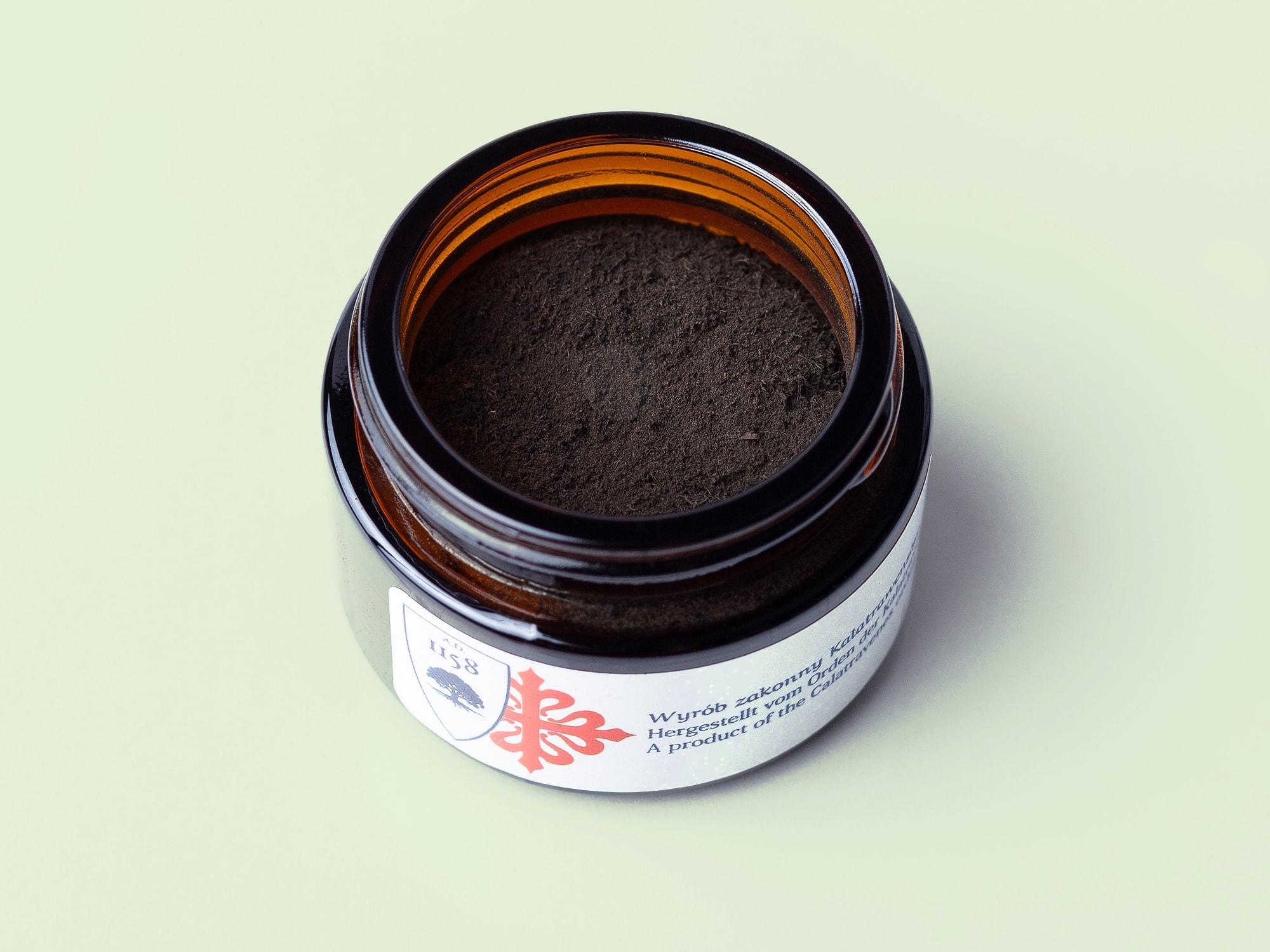 Offene Dose mit dunkelbraunem Mooreichen-Pulver